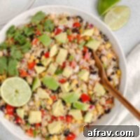 A vibrant bowl of Zesty Southwest Quinoa Salad with Avocado, garnished with fresh cilantro and a lime wedge.