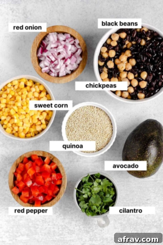 Assorted fresh ingredients for the quinoa salad, including cooked quinoa, black beans, chickpeas, corn, red pepper, red onion, and cilantro.