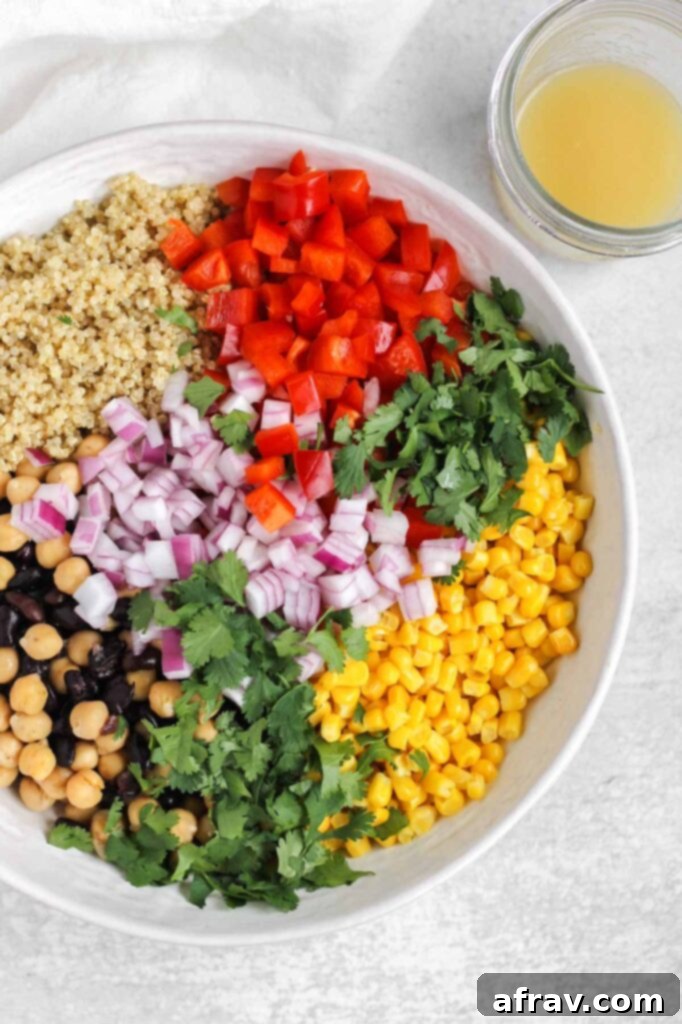 All the salad ingredients, including quinoa, beans, corn, and chopped vegetables, gathered in a large mixing bowl before dressing.