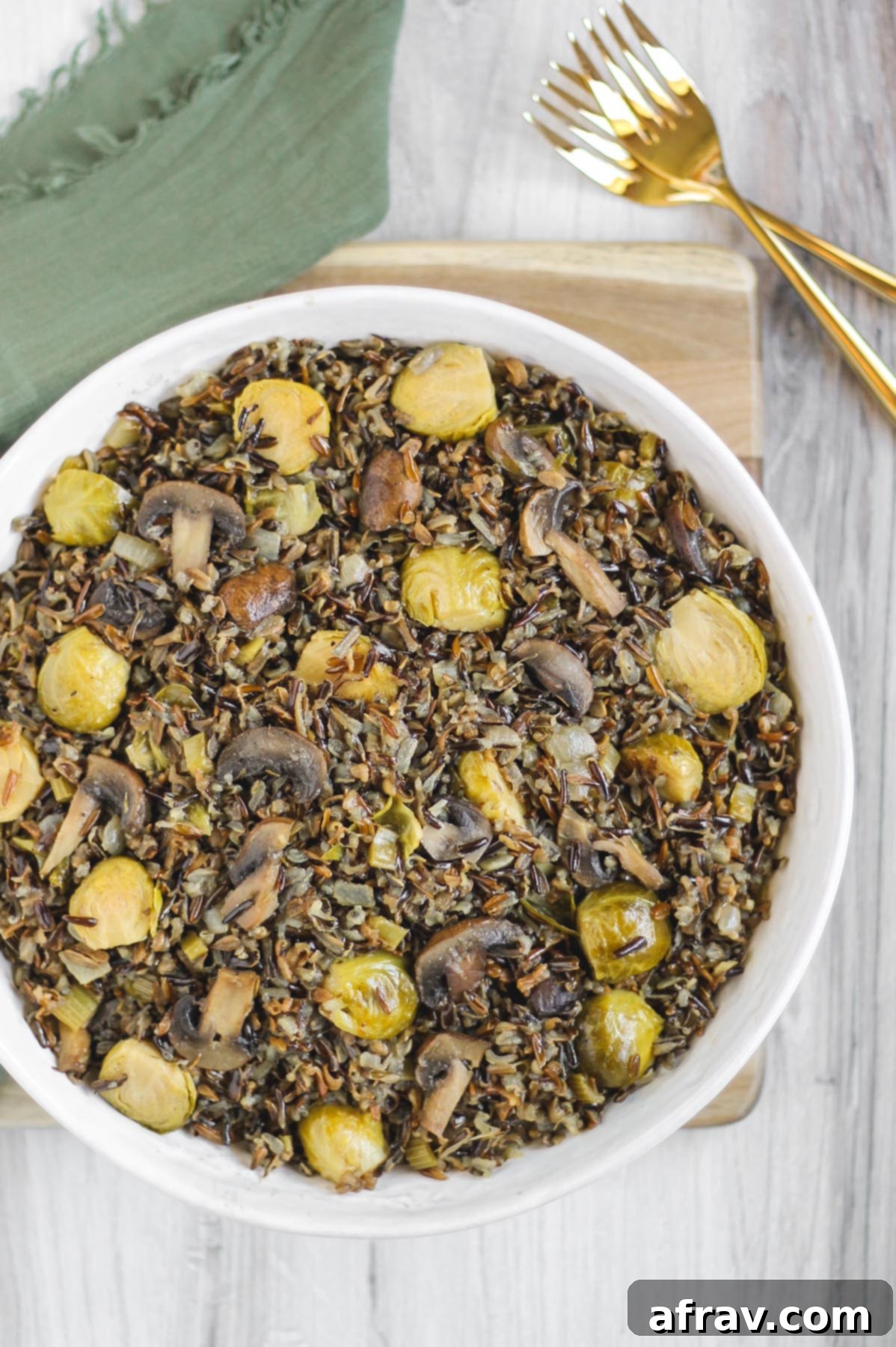 Slow-Cooked Wild Rice Delight 5 Close-up of cooked wild rice pilaf in a large white bowl, featuring tender Brussels sprouts, sautéed mushrooms, and herbs