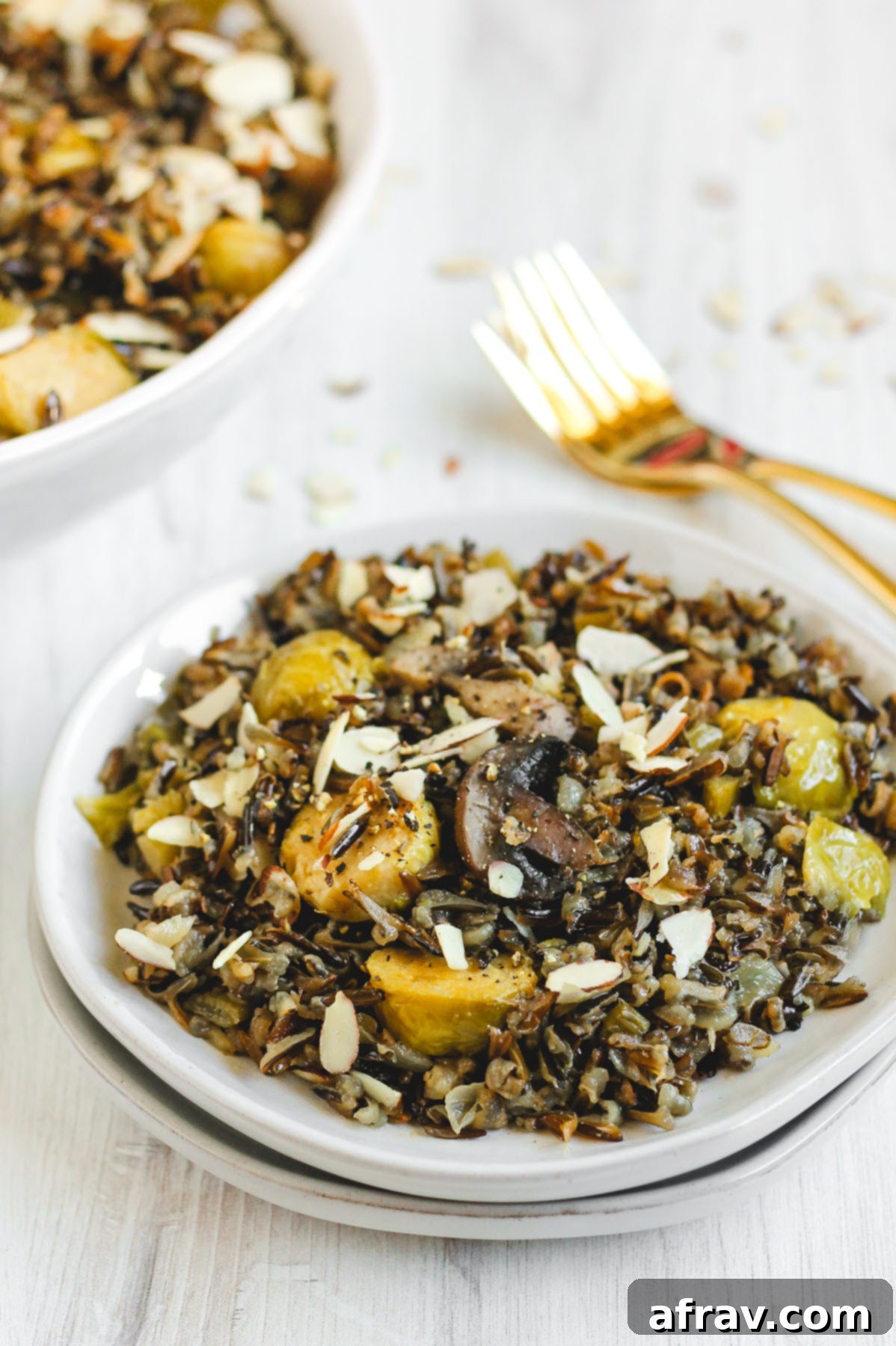 Slow-Cooked Wild Rice Delight 6 Single serving of slow cooker wild rice pilaf on a small white plate, garnished with toasted almonds and two elegant gold forks in the background
