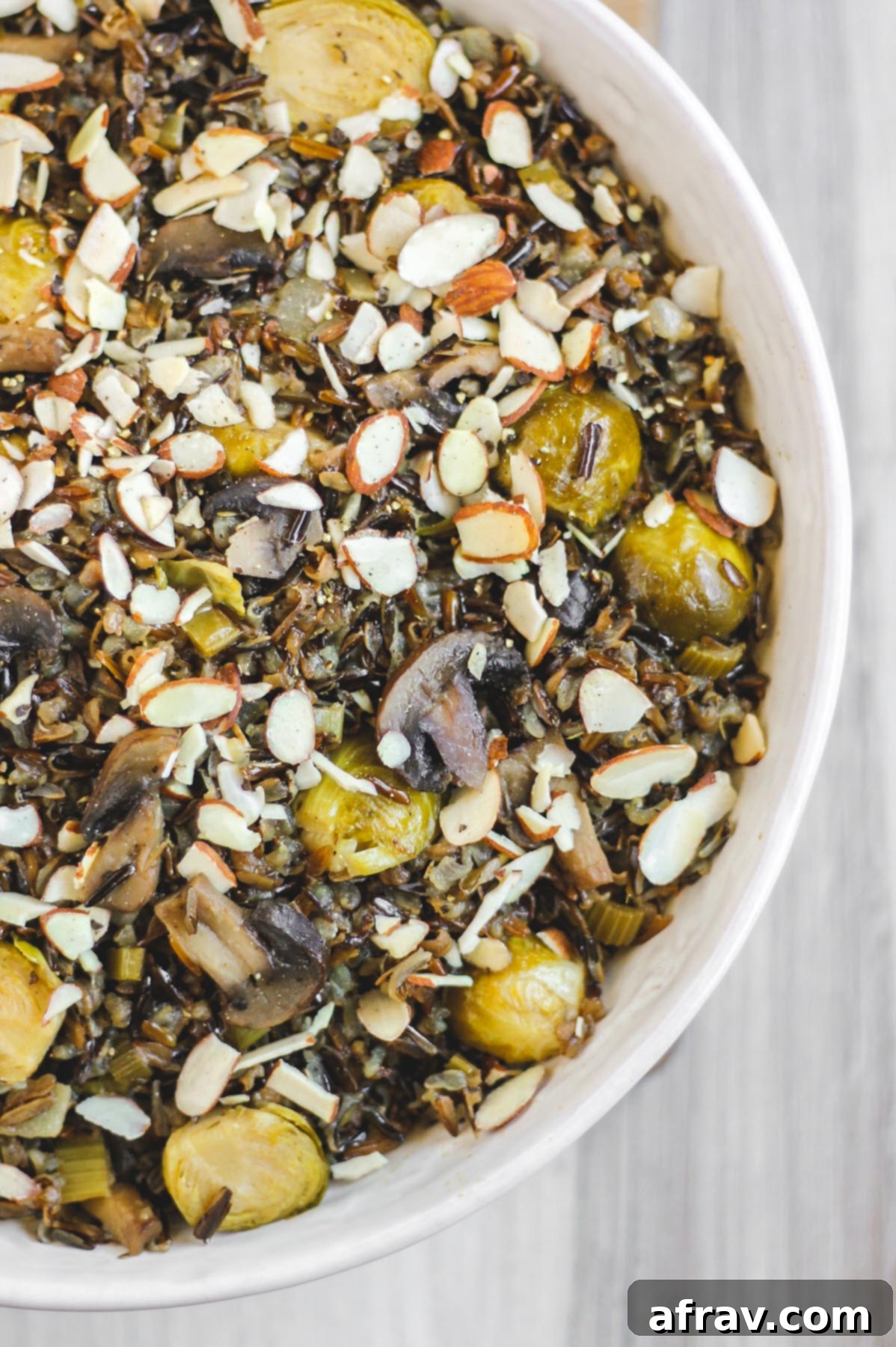 Slow-Cooked Wild Rice Delight 7 Close-up view of fluffy, perfectly cooked wild rice pilaf with visible tender Brussels sprouts and sliced mushrooms in a large white serving bowl