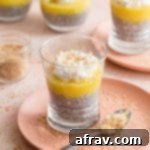 Pineapple Coconut Chia Pudding in a glass on a pink plate with other puddings in the background.