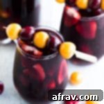 Sparkling Berry Cherry Kombucha Sangria 2 Up-close view of Berry Cherry Kombucha Sangria in cocktail glasses on a white, wooden surface.