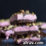Up-close view of a stack of Frozen Strawberry Goat Cheese Bars on a dark surface with a dark background.