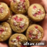 Zesty Raspberry Lemon Muffins 2 Close up view of raspberry lemon muffins in a basket lined with a pink cloth, showcasing their perfectly baked tops and rich color.