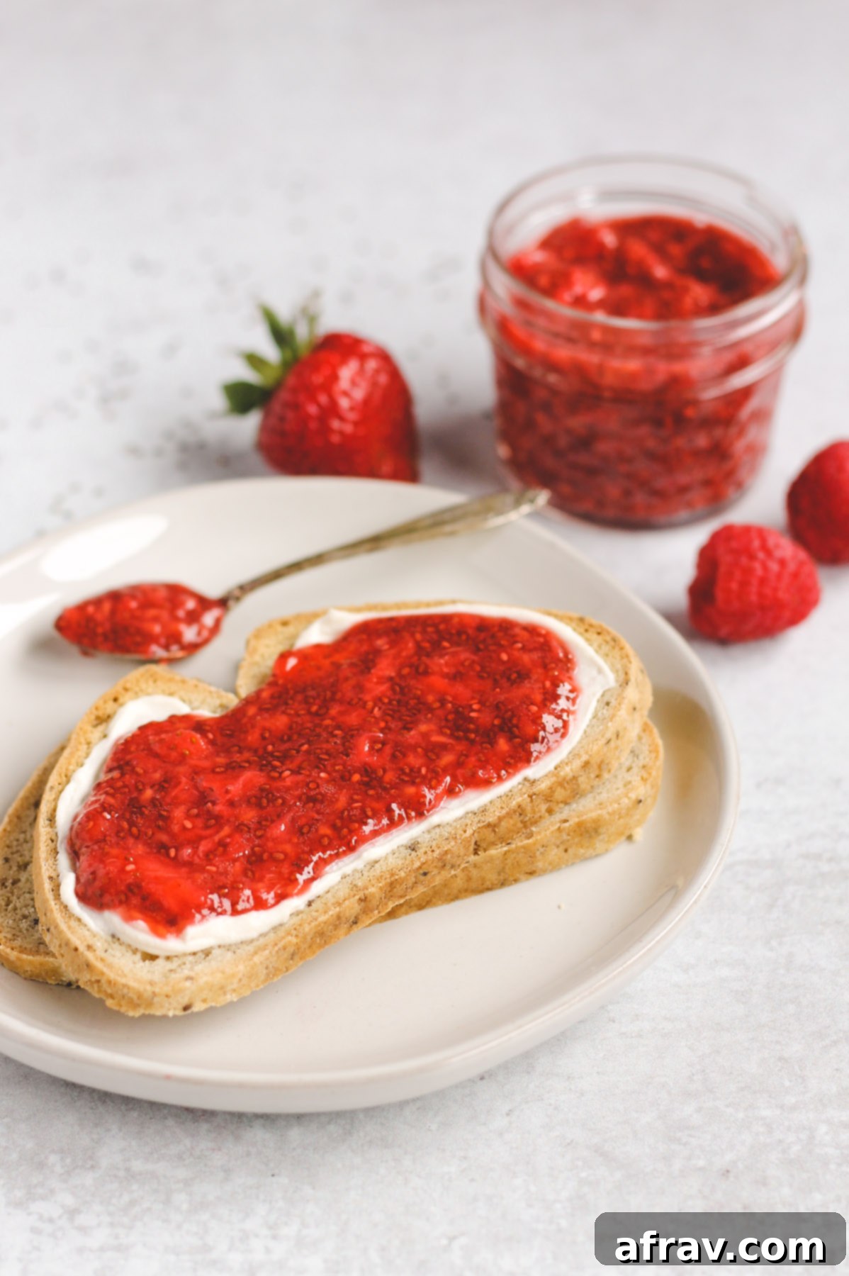 two slices of toast, stacked on top of each other; top toast with cream cheese and jam spread on it