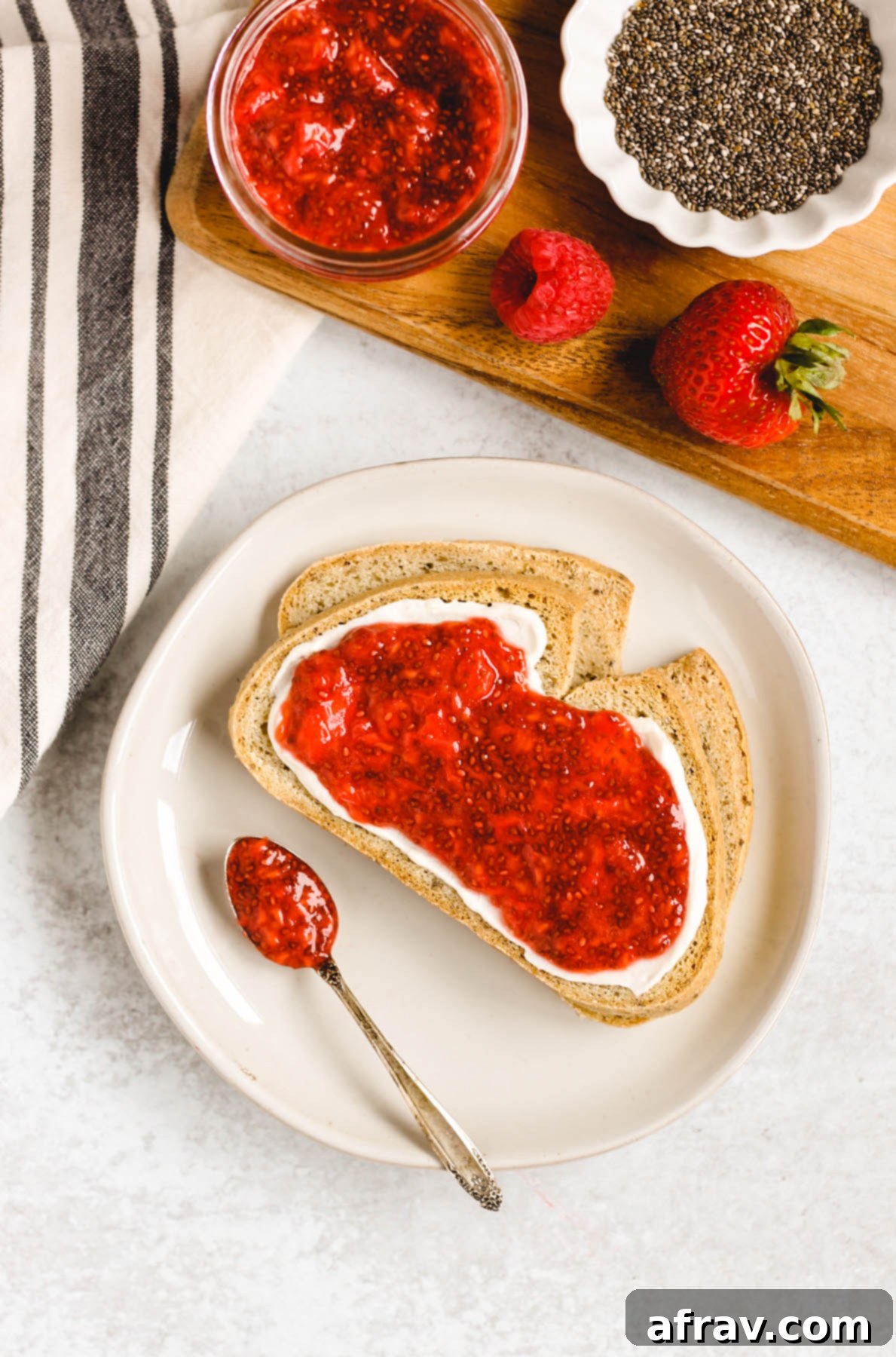 two slices of toast on a plate with cream cheese and berry chia jam spread on toast