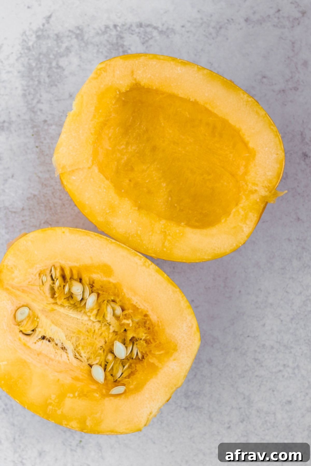 One spaghetti squash cut in half with the middle part removed from one side of the squash.