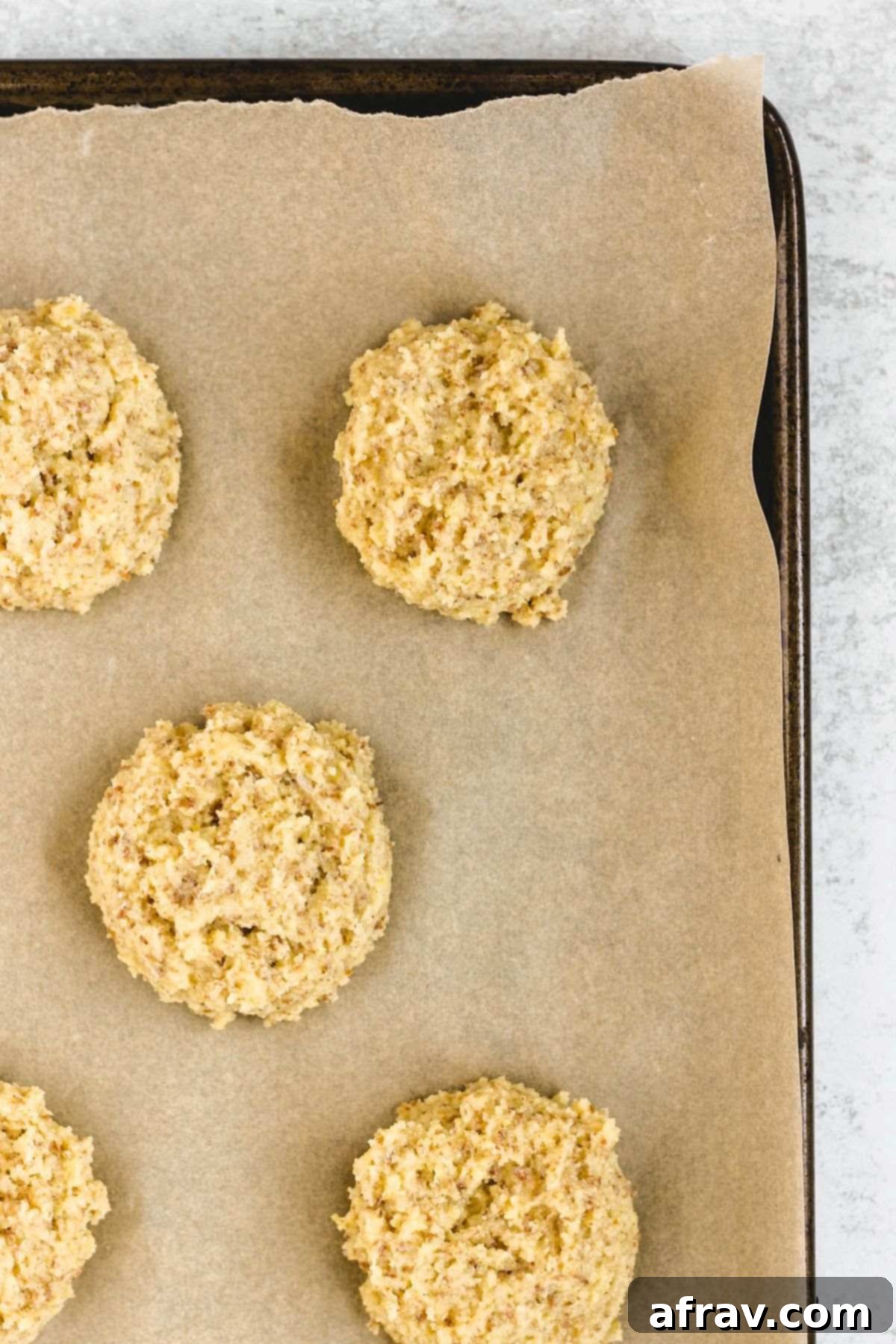 Fluffy Paleo Almond Flour Biscuits 7 Almond flour drop biscuits on a baking sheet, spaced apart, before being baked.