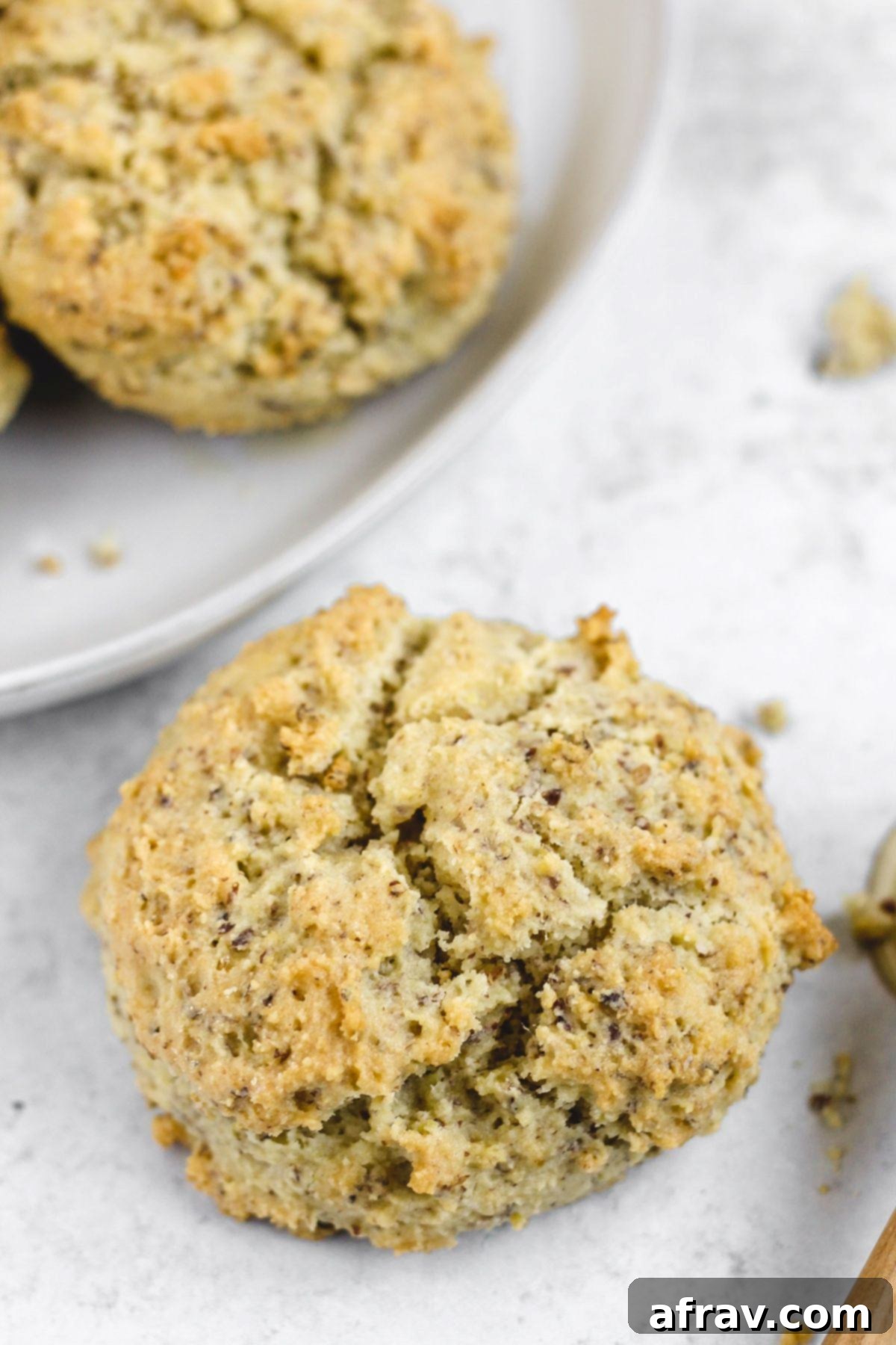 Fluffy Paleo Almond Flour Biscuits 8 Single almond flour biscuit with a plate of biscuits in the background, showing its tender interior.