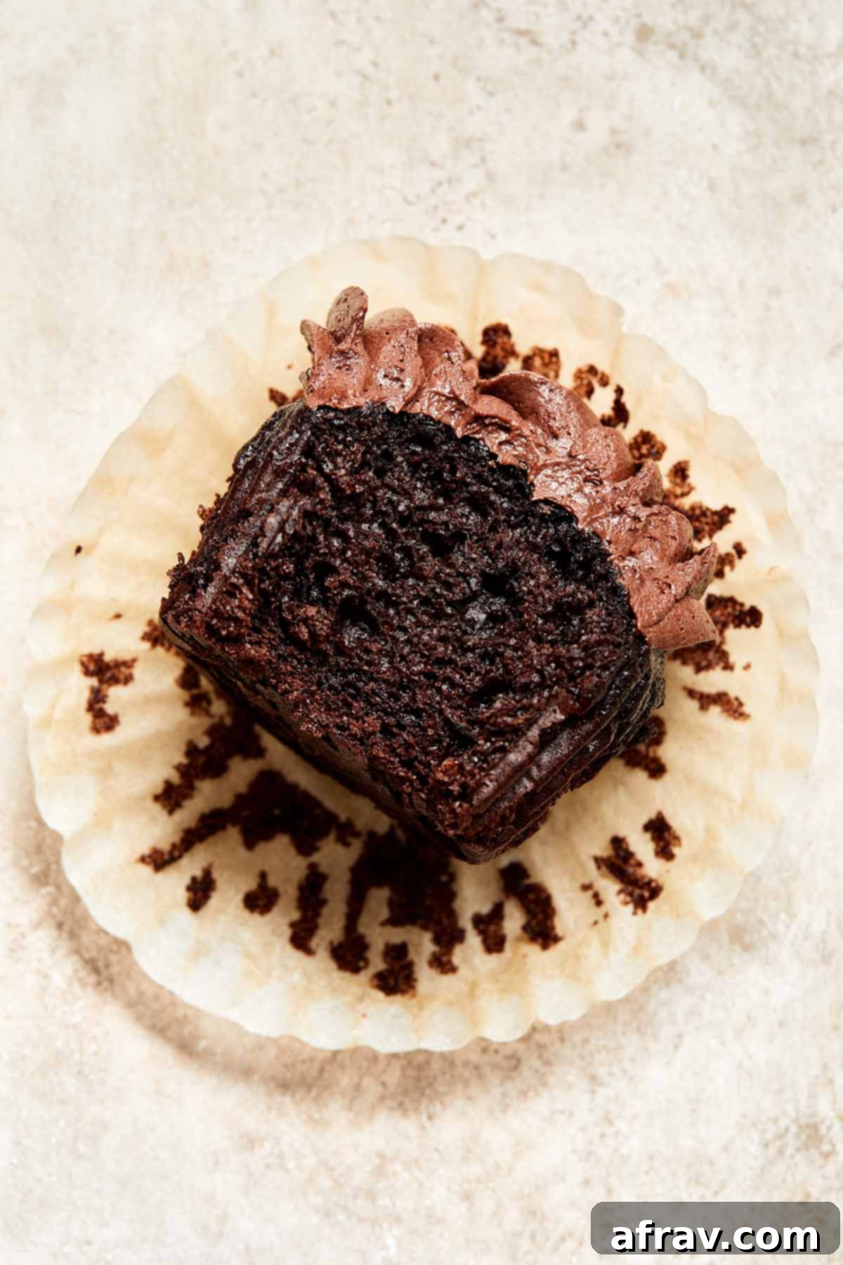 Irresistibly Moist Chocolate Zucchini Cupcakes 2 Close up view of a decadent chocolate zucchini cupcake in a wrapper with a bite taken out of it, revealing its fudgy texture.