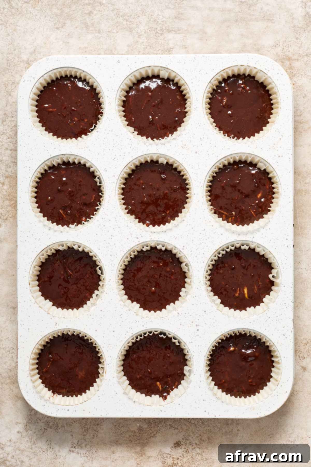 Irresistibly Moist Chocolate Zucchini Cupcakes 5 Cupcake batter, perfectly portioned into a 12-cup muffin pan, ready for baking. Each liner is about three-quarters full, ensuring optimal rise for these chocolate zucchini cupcakes.