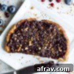 Overhead view of Blueberry Pomegranate Chia Jam on a slice of toast that's on a white plate.