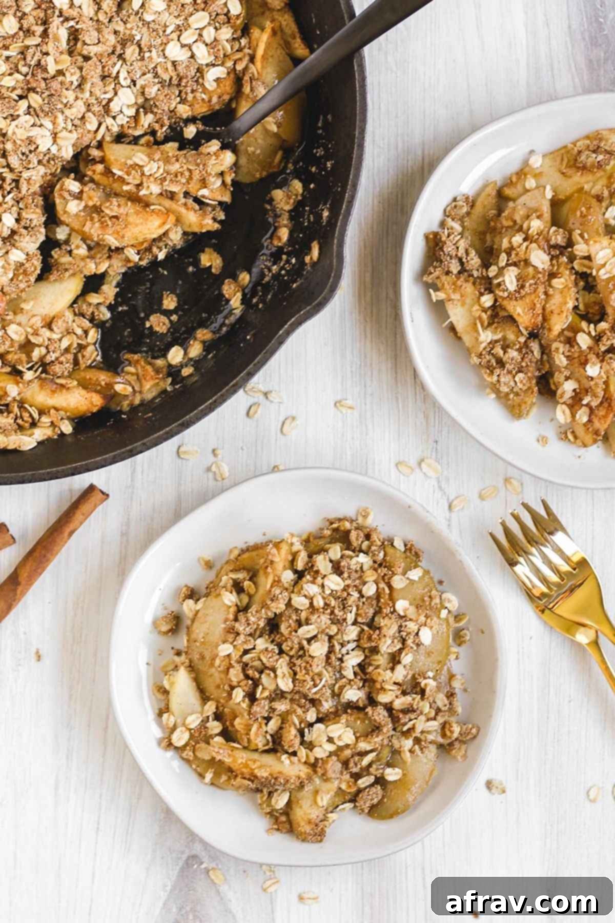 Wholesome Gluten-Free Apple Crisp Made Easy 6 A cast iron skillet of baked apple crisp, with two small plates of apple crisp next to it, invitingly arranged.