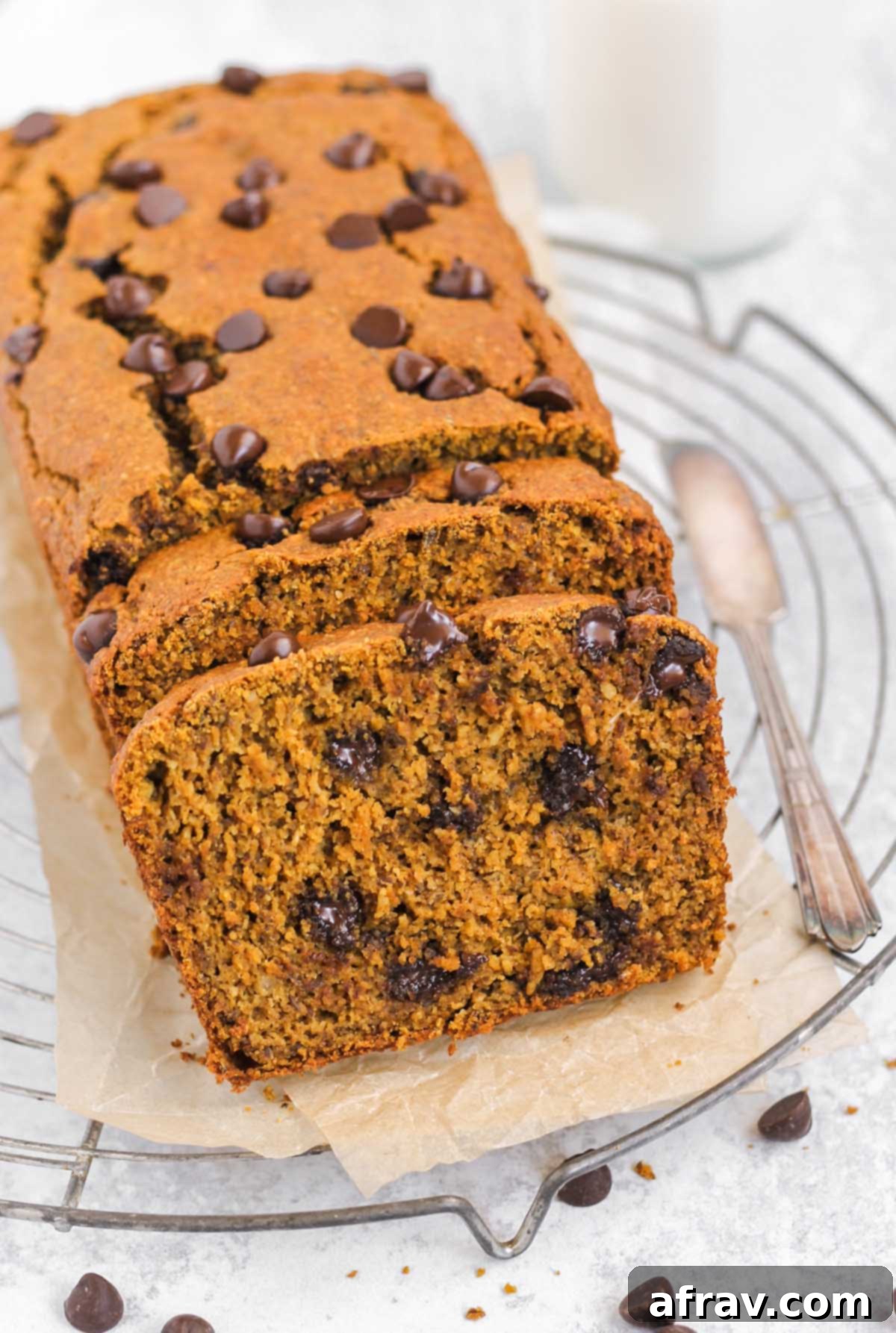 Irresistible Gluten Free Chocolate Chip Pumpkin Bread 11 Half sliced loaf of pumpkin chocolate chip bread, showcasing its fluffy interior and melted chocolate.