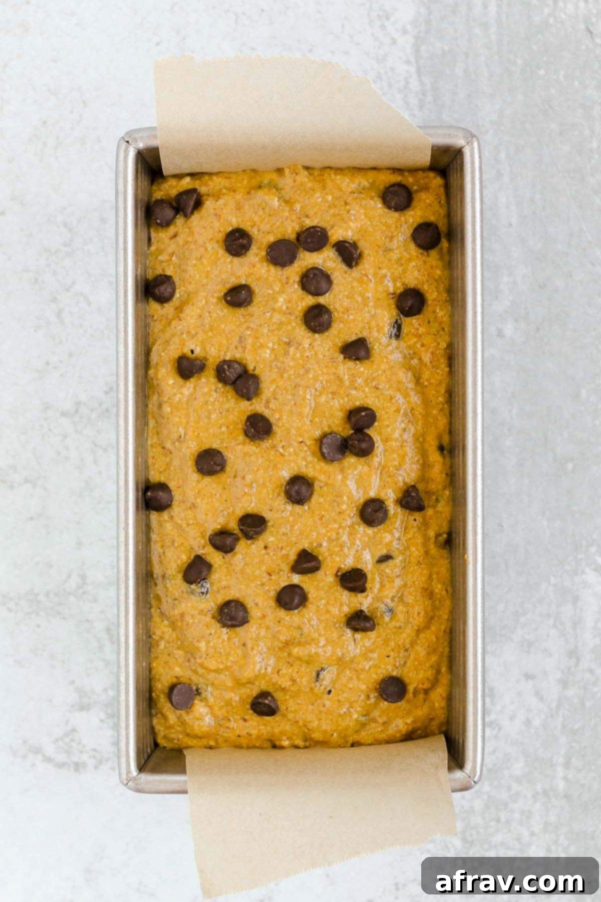 Irresistible Gluten Free Chocolate Chip Pumpkin Bread 8 Loaf pan with pumpkin bread batter sprinkled with chocolate chips, ready for baking.