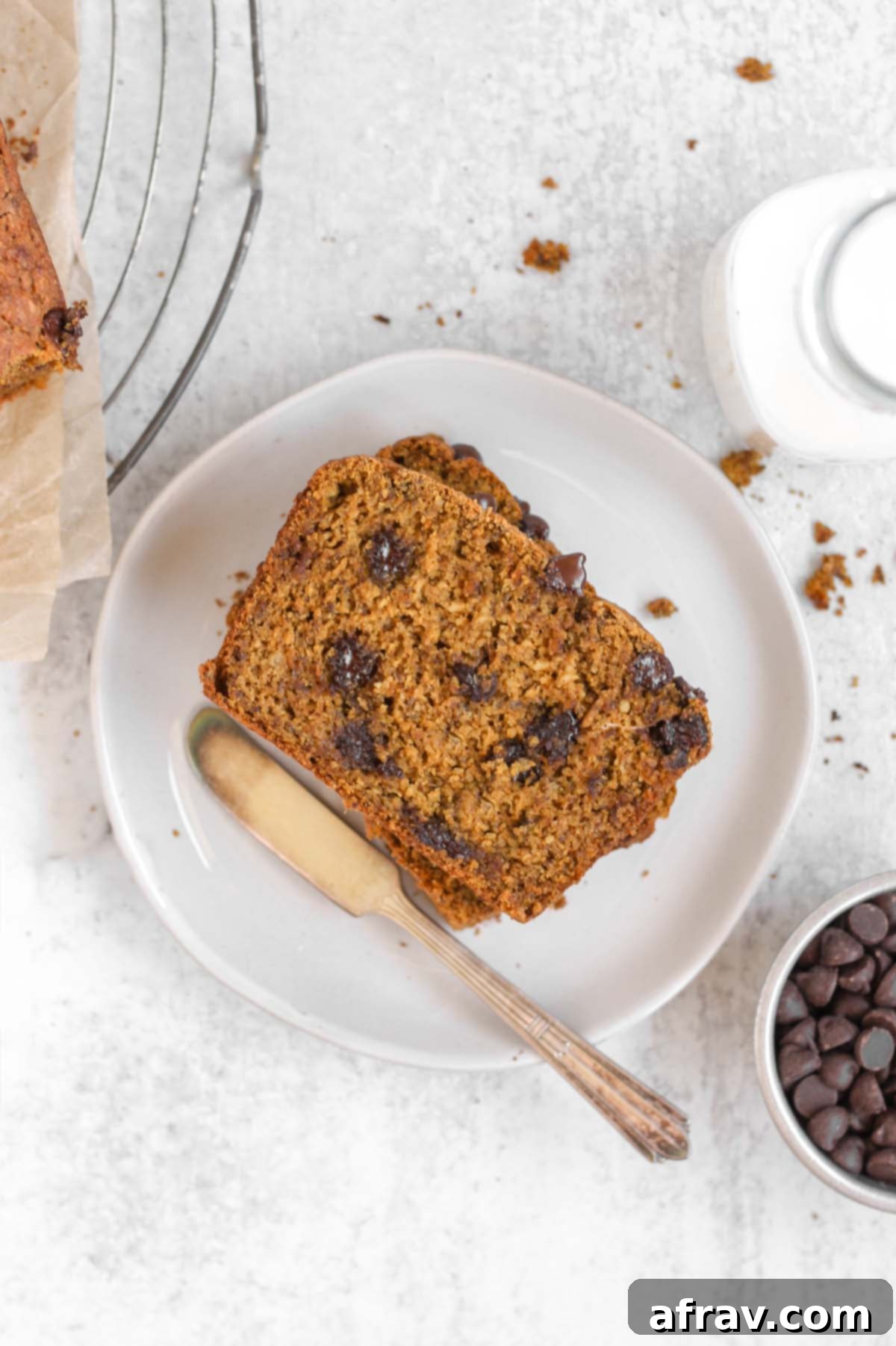 Irresistible Gluten Free Chocolate Chip Pumpkin Bread 10 Overhead view of a perfectly baked and sliced piece of gluten-free pumpkin chocolate chip bread on a white plate, showcasing its soft texture and melted chocolate chips.