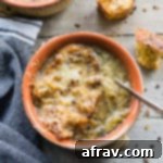 Overhead view of Easy Bone Broth French Onion Soup in an orange bowl.