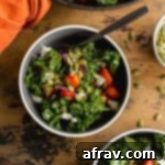 Up close view of roasted root vegetable salad in grey bowls, featuring a rich array of colors and textures from the vegetables, kale, goat cheese, and pumpkin seeds.