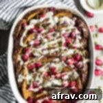 Overhead view of Cranberry Pumpkin French Toast Bake in a white baking dish surrounded by a white and blue striped hand towel.