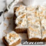 Vegan Chai Cake topped with coconut whip and toasted coconut and cut into squares.