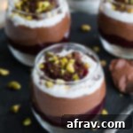 Dairy-Free Cheesecake Dreams: Chocolate Raspberry Parfaits 2 Side view of Chocolate Raspberry Cheesecake Parfaits on a dark surface.