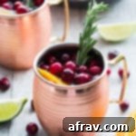 Orange Cranberry Kombucha Moscow Mules in copper mugs, ready to be served at a holiday party.