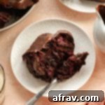 Slice of vegan chocolate cranberry bundt cake on a white plate with a fork.