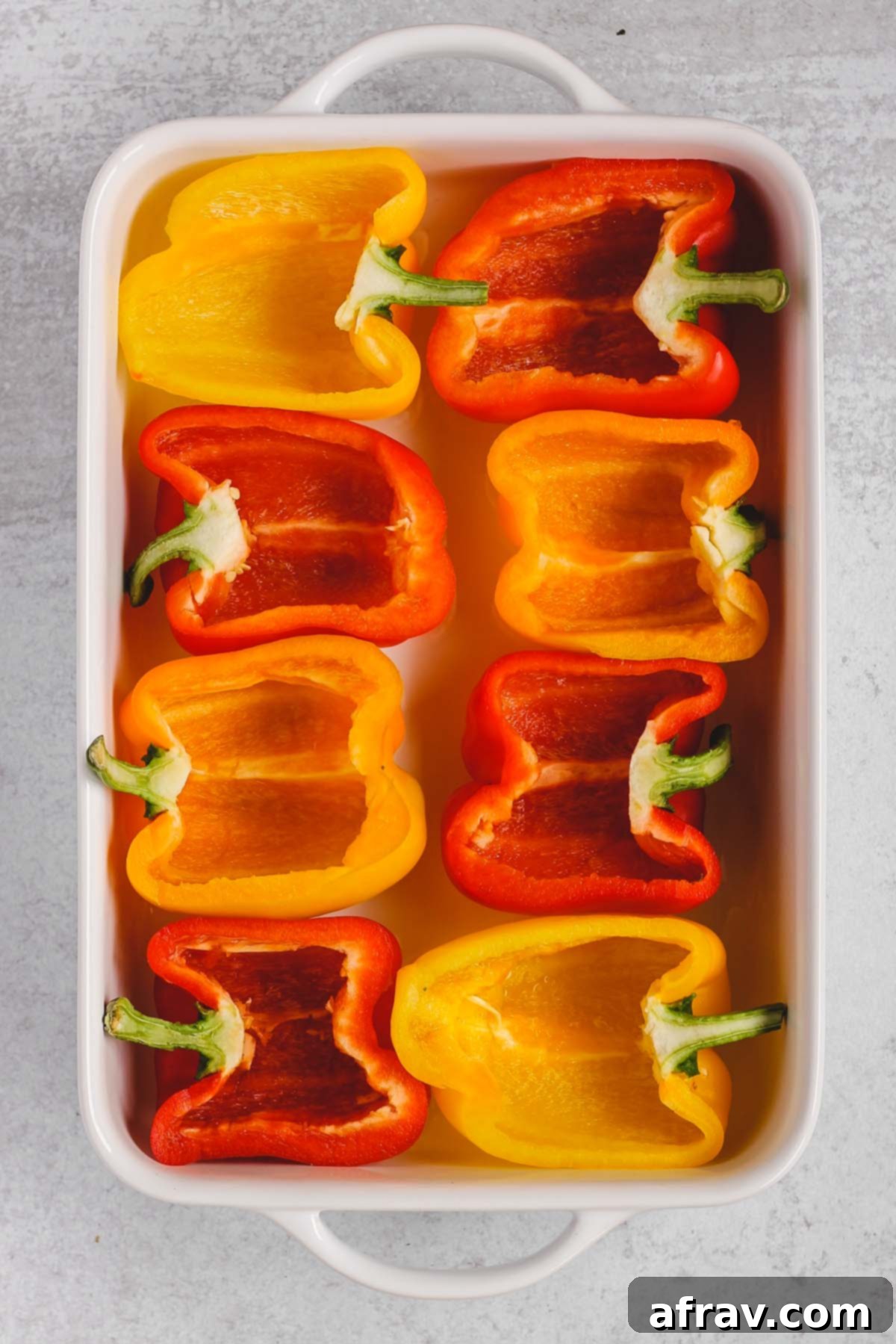bell peppers cut in half lying in a white baking dish