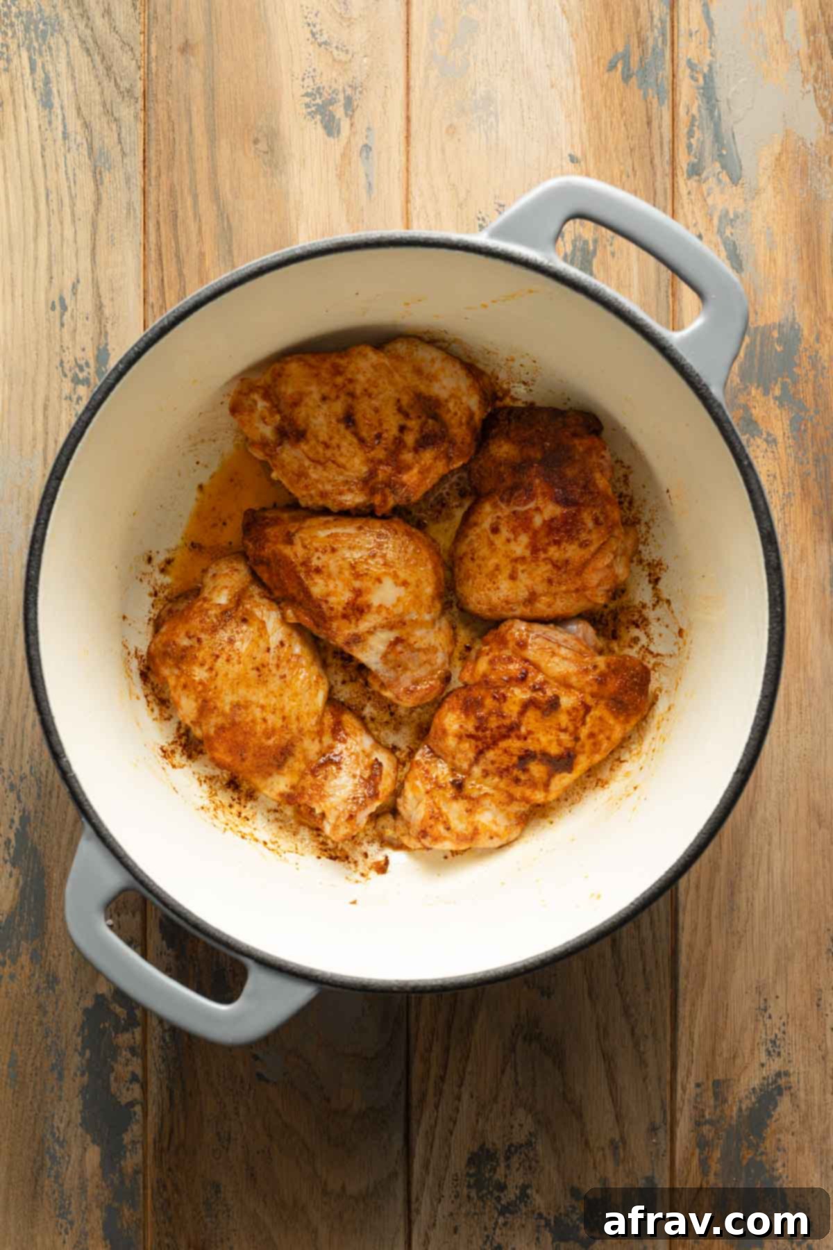 Browned chicken thighs in a Dutch oven.