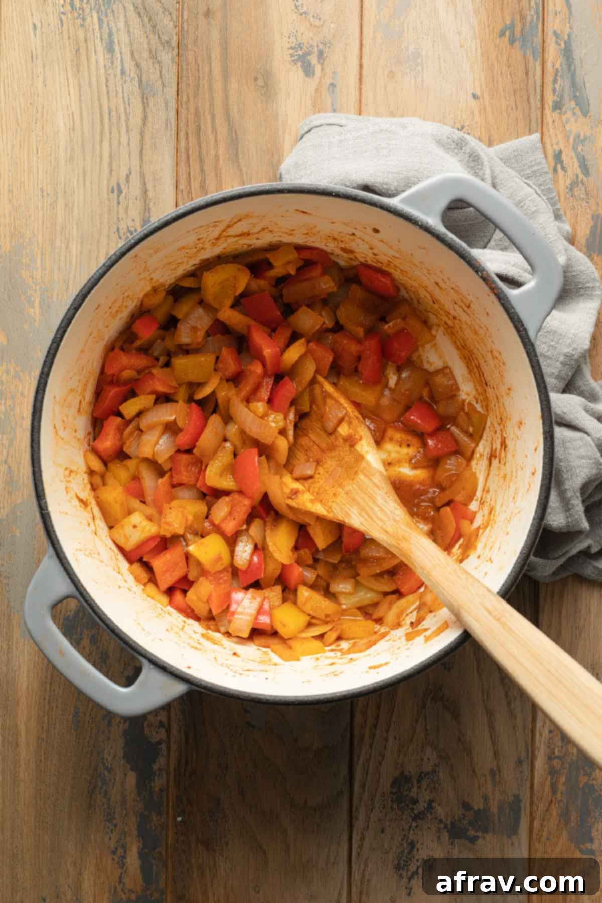 Peppers and onions being sautéed in a large pot.