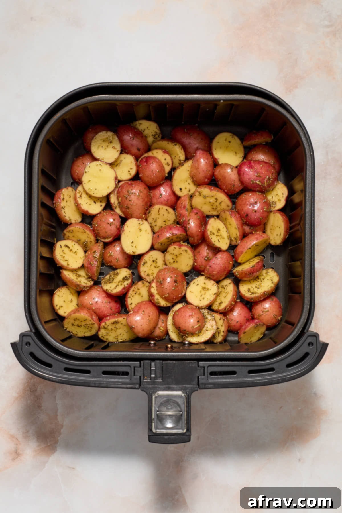 Seasoned baby potatoes in the air fryer basket.