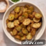 Air fryer baby potatoes served in a white bowl and topped with sea salt and chopped fresh parsley.