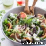 Grapefruit Salad with Cilantro and Goat Cheese in a large grey bowl with a jar of cilantro dressing in the background.