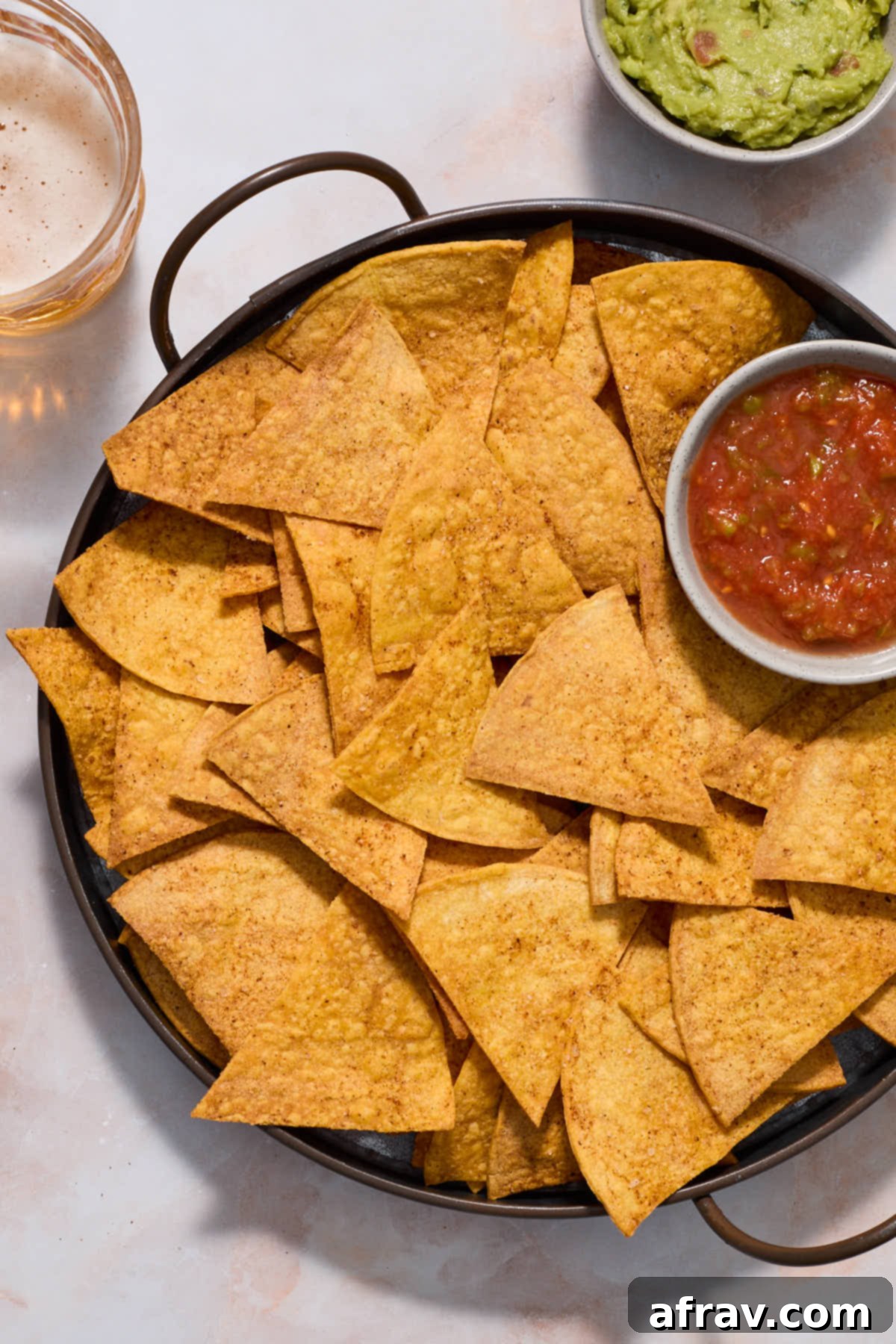 Overhead of tortilla chips served with guacamole and salsa.