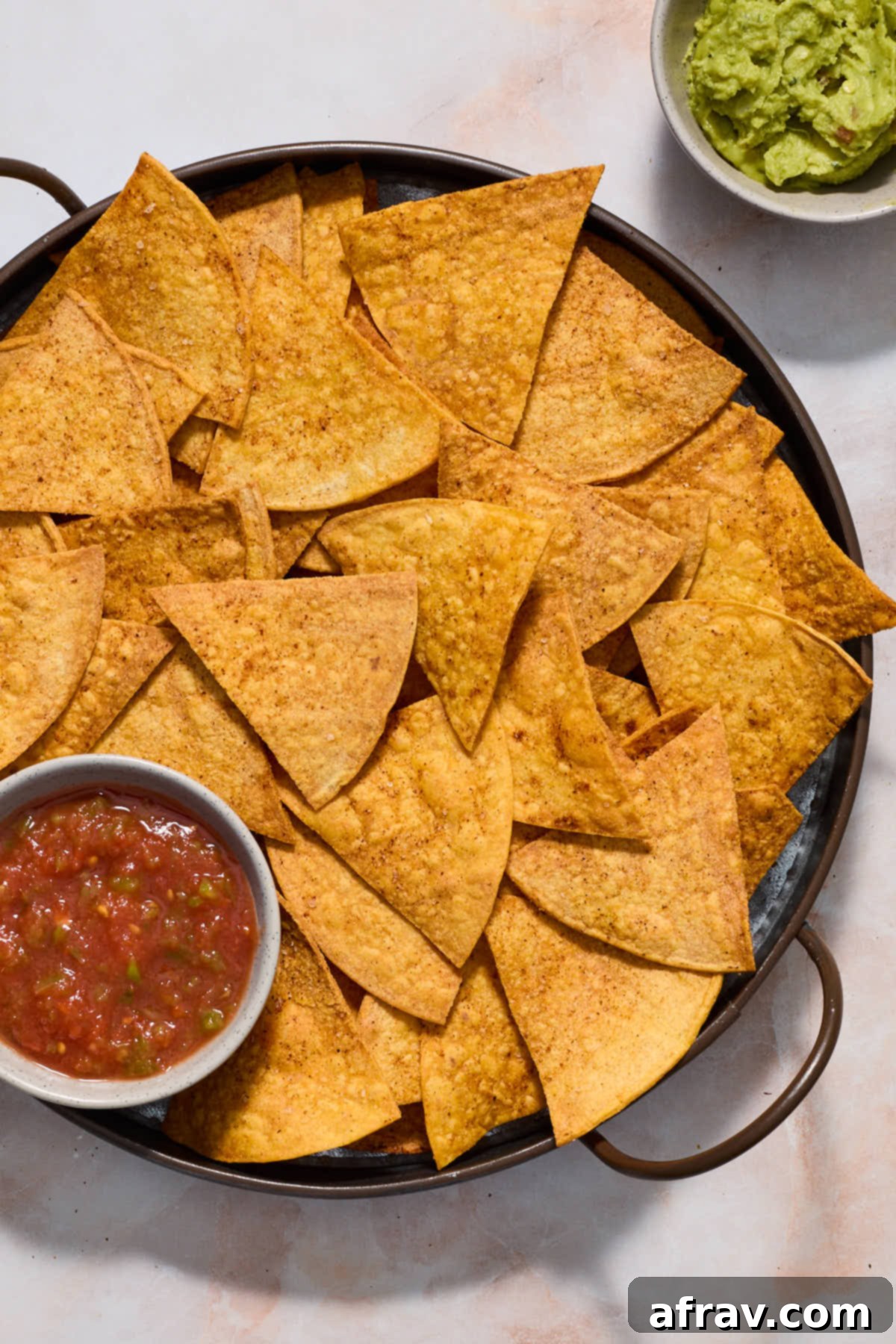Tortilla chips on a platter and served with salsa.
