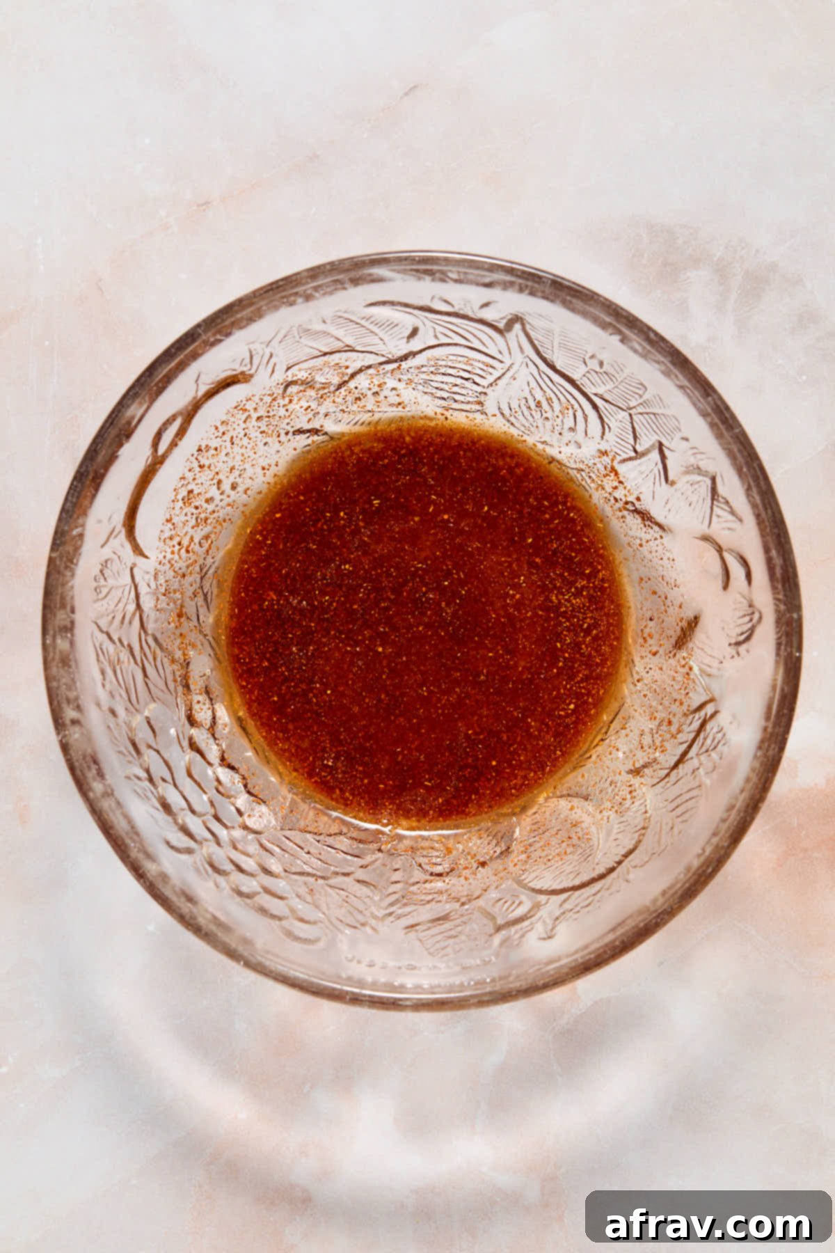 Oil and seasonings mixed together in a small glass bowl.