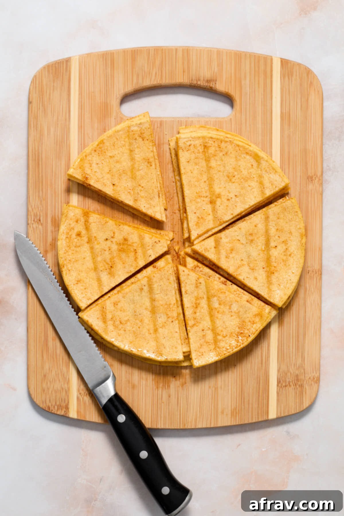 Seasoned tortillas cut into triangles on a wooden board.