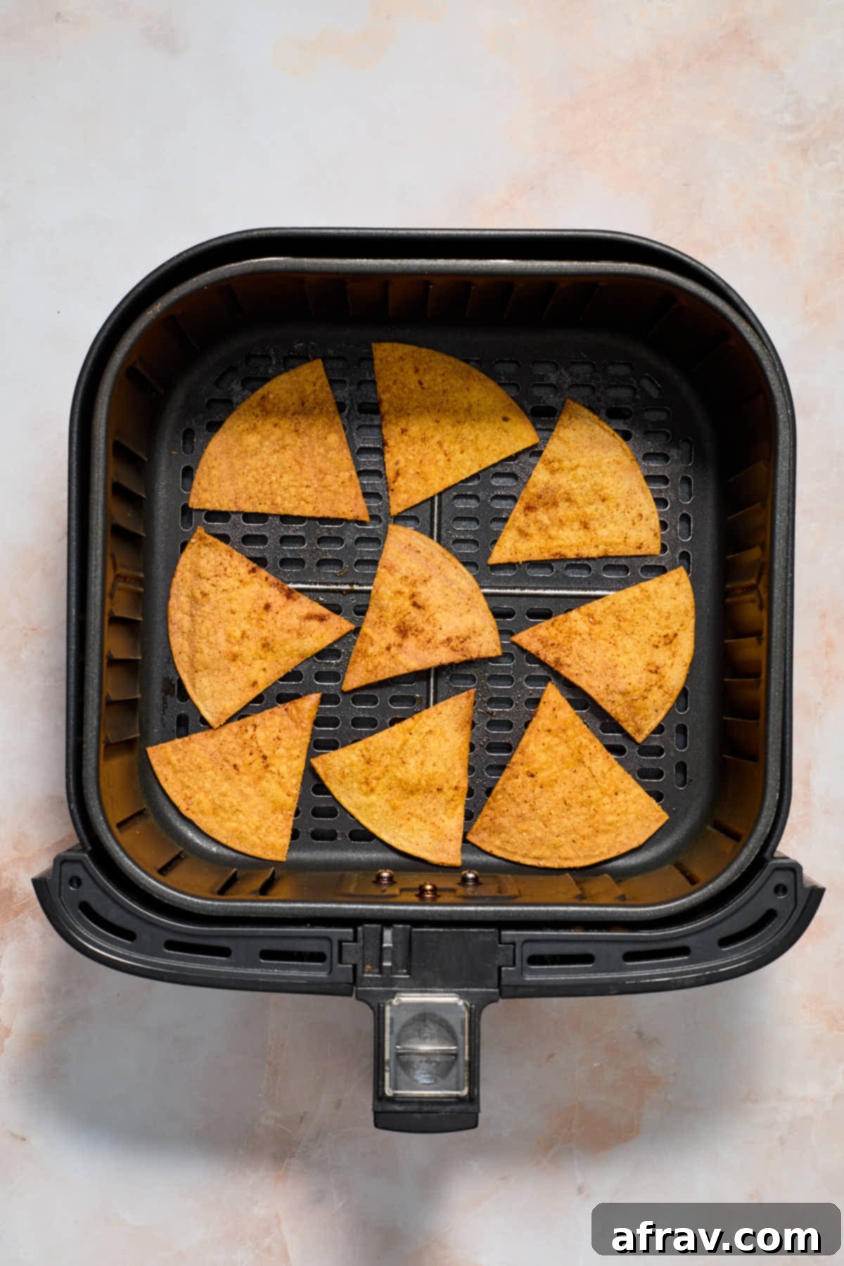 Air fried tortilla chips in an air fryer basket.