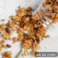 Homemade oat and honey granola spilling out of a mason jar, highlighting its crunchy texture.
