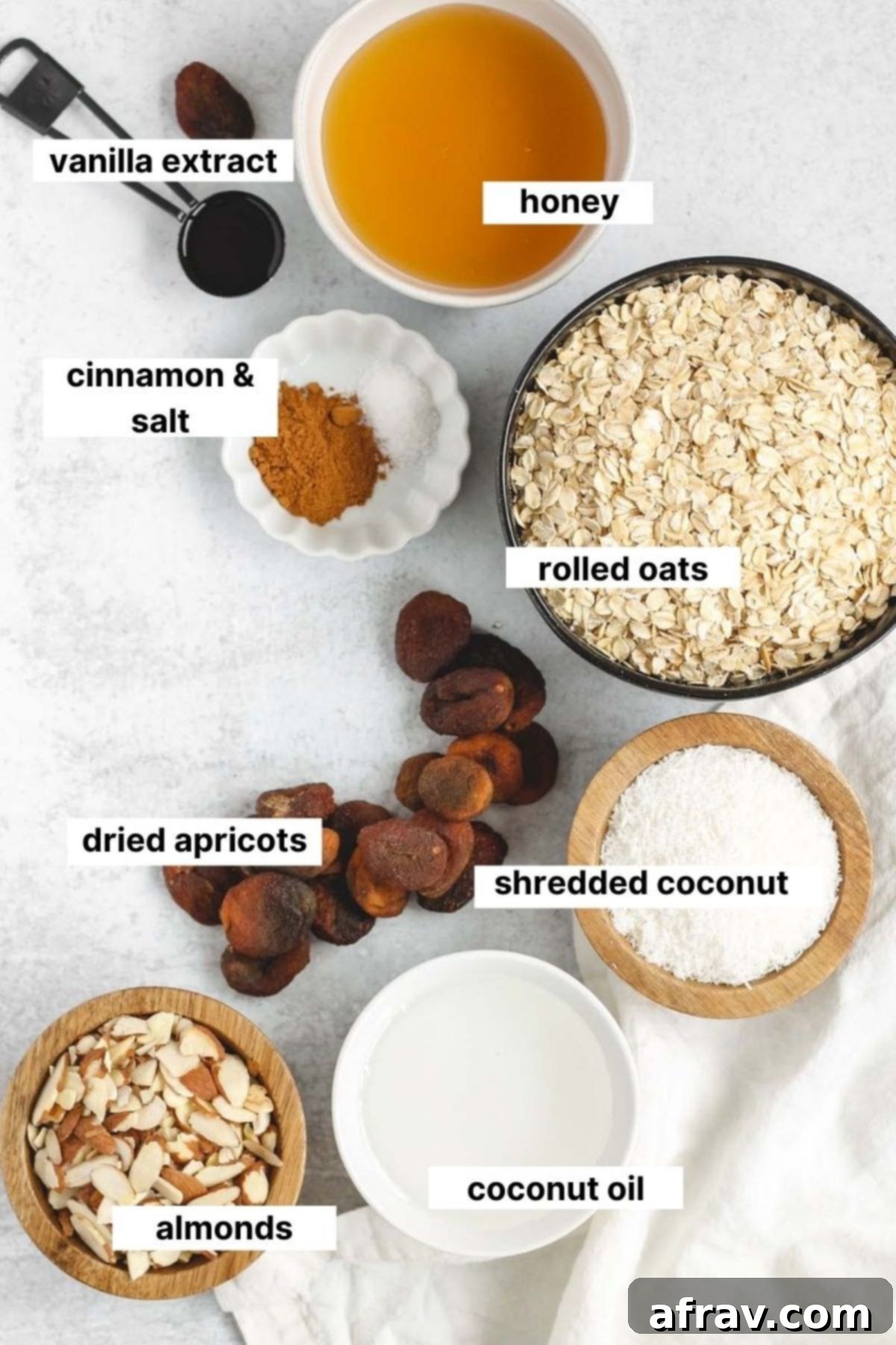 Arrangement of labeled ingredients for oat and honey granola, including oats, almonds, coconut, honey, and coconut oil.