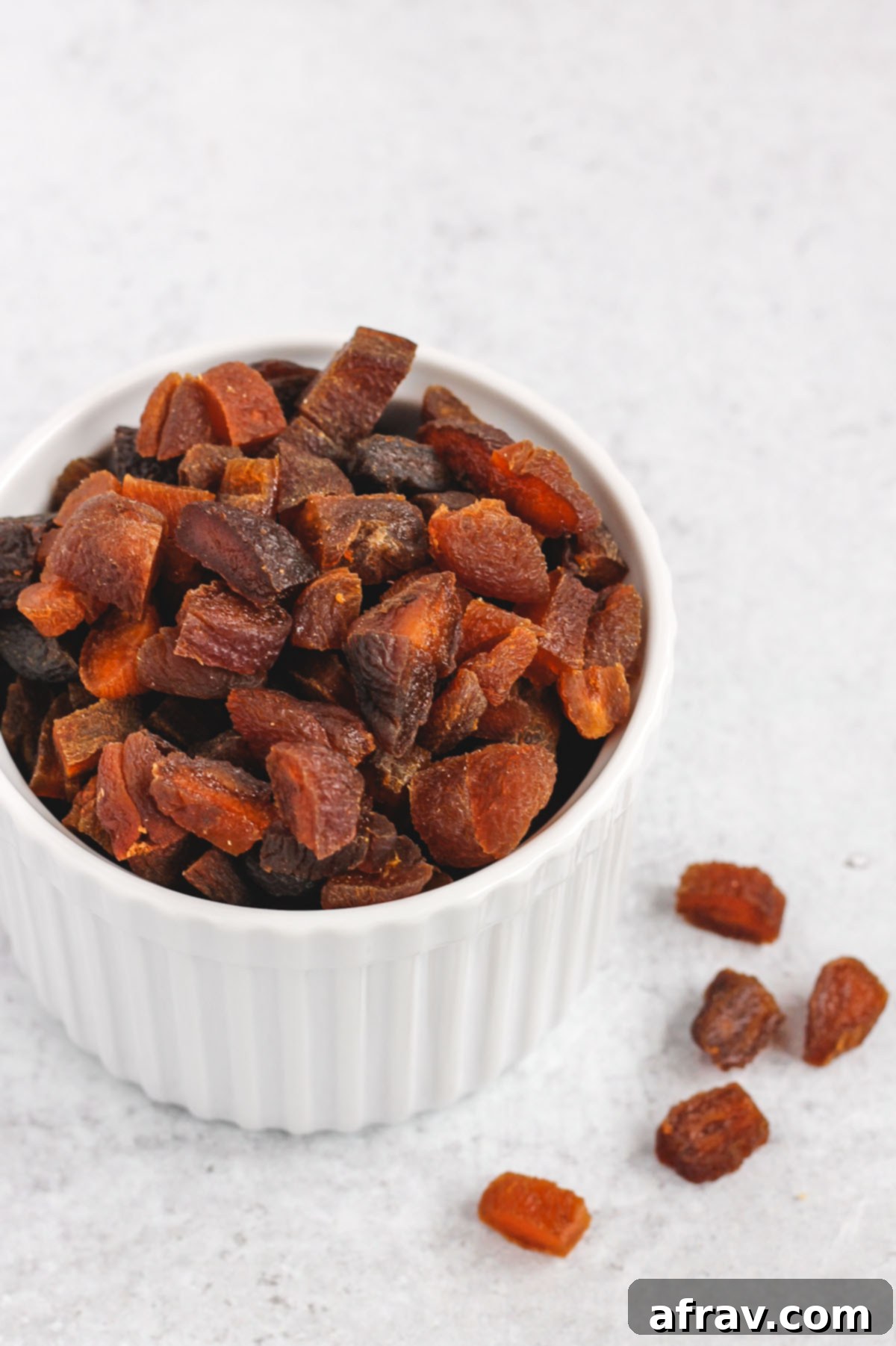 Small white bowl filled with finely chopped dried apricots, ready to be added to cooled granola.
