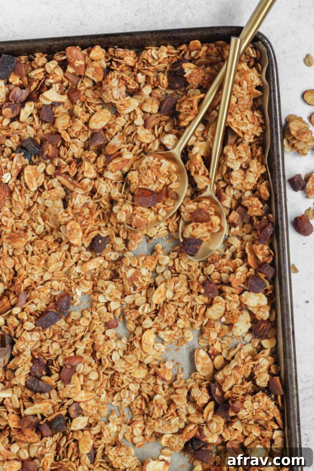 Freshly baked oat and honey granola cooling on a baking sheet, showing its golden-brown color.