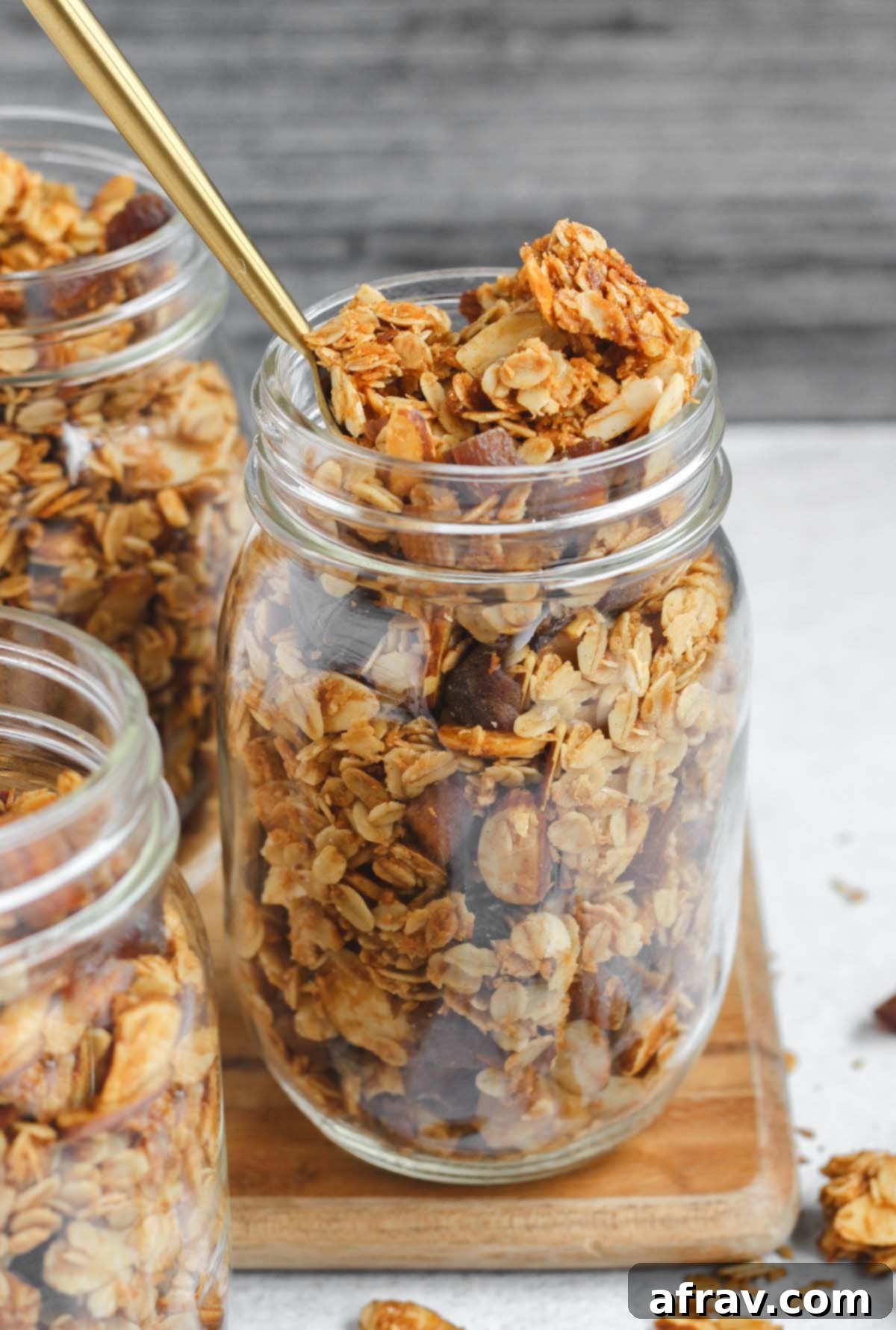 Three mason jars filled with homemade oat and honey granola, showcasing the perfect clusters and readiness for storage or gifting.