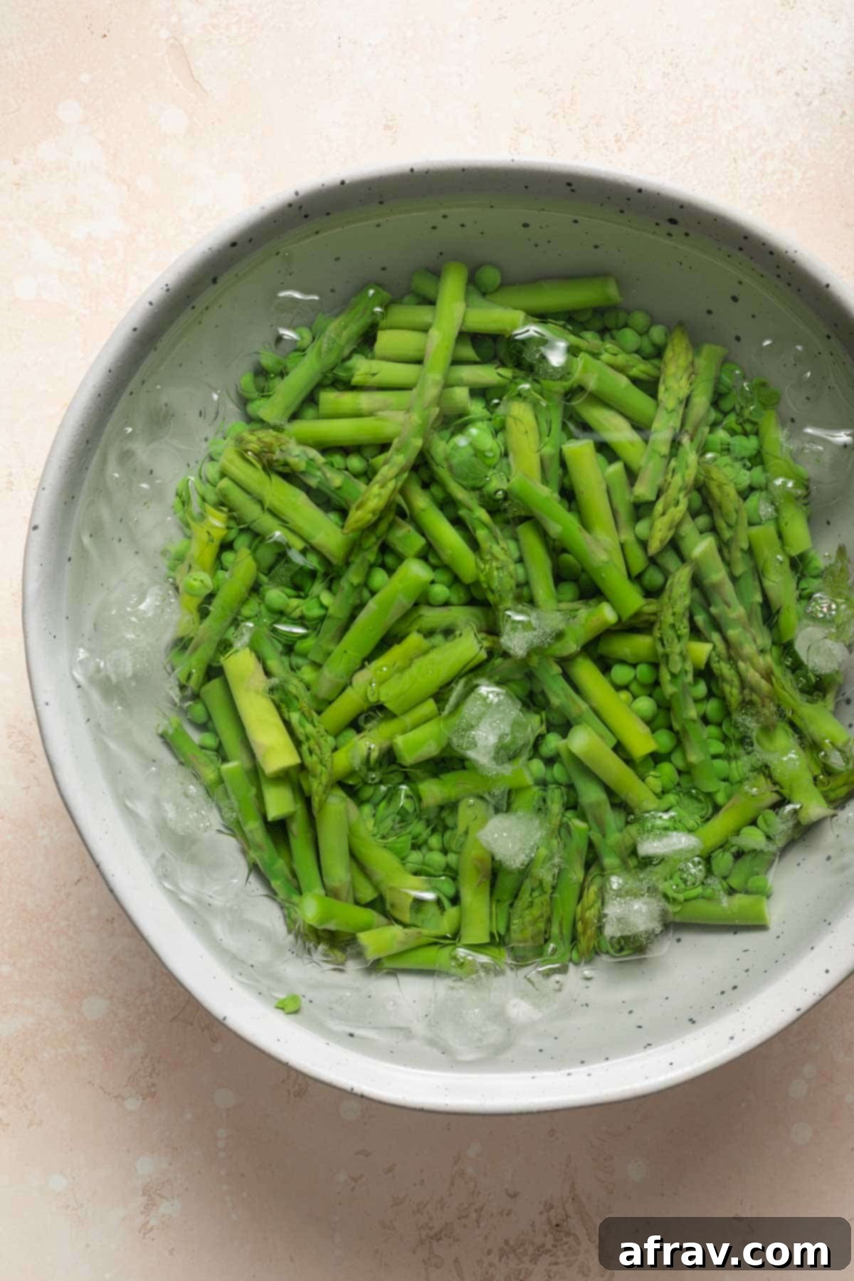 Peas and asparagus being shocked in an ice bath.
