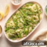 Lemon garlic pasta with peas and asparagus served on an oval plate.