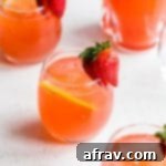 Glasses of strawberry rhubarb gin fizz arranged on a light coloured surface.
