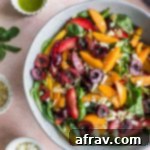 Overhead view of stone fruit salad in a large grey bowl on a pink surface.