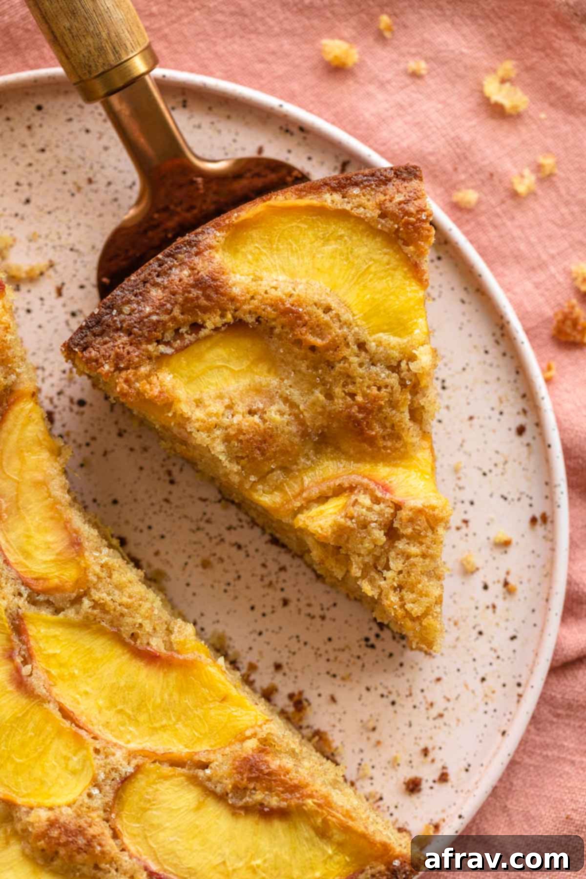 Up close of a slice of peach cake, revealing its moist texture and juicy peaches.